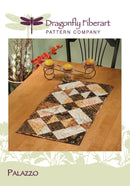Patchwork table runner on a wooden table with 'Dragonfly Fiberart Pattern Company' branding.
