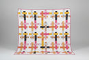Colorful quilt with geometric pattern displayed on a stand.