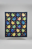 Colorful quilt with bird pattern held up against a neutral background